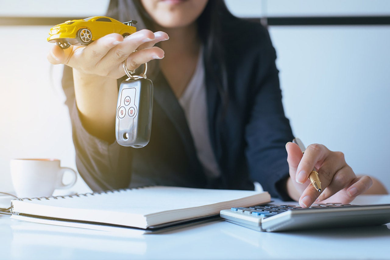 Used Car Financing | Woman calculating car payments and holding yellow toy car